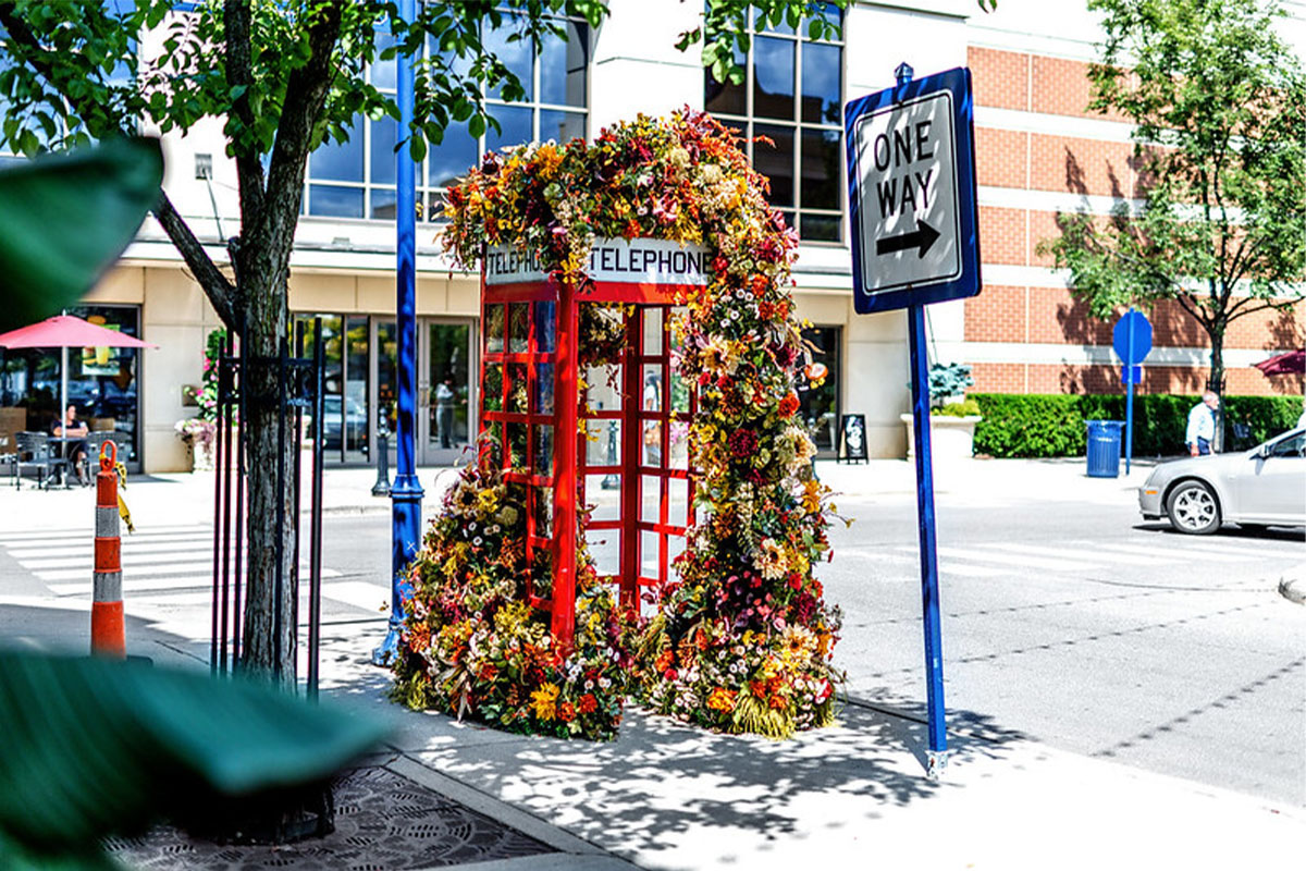 Public art installation of a phone booth covered in flowers at Easton