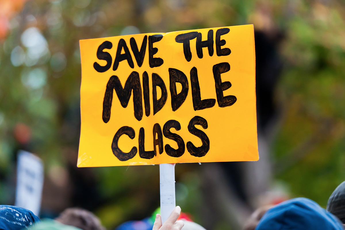 Hand holding up a yellow sign that says "Save the Middle Class"
