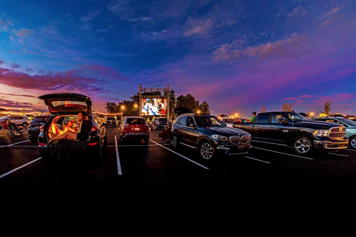 Cars in a parking lot at sundown for a drive-up movie