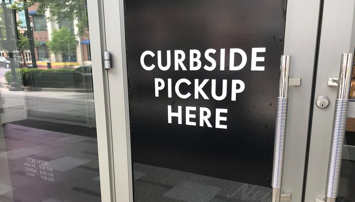 Restaurant door with a window decal that says "Curbside pickup here"