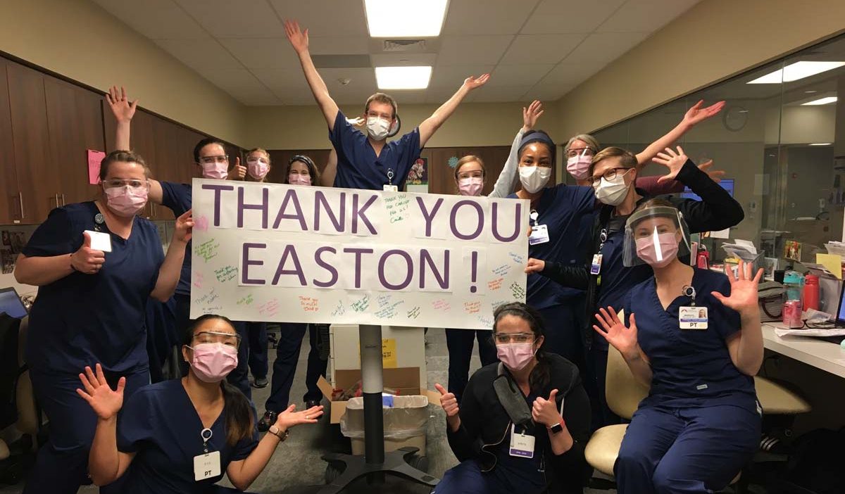 A group of nurses wearing masks holding a sign that says "Thank you Easton" that is signed by the community