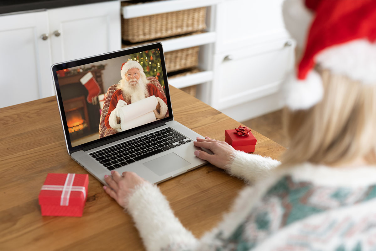 Woman using a laptop computer with an image of Santa Claus on the screen