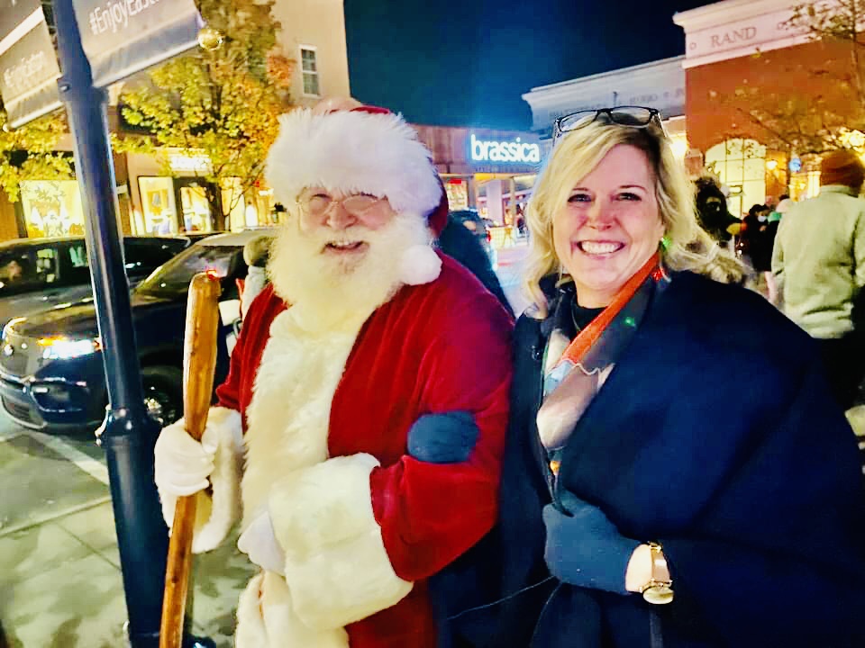 Woman smiling next to Santa Claus outdoors at Easton