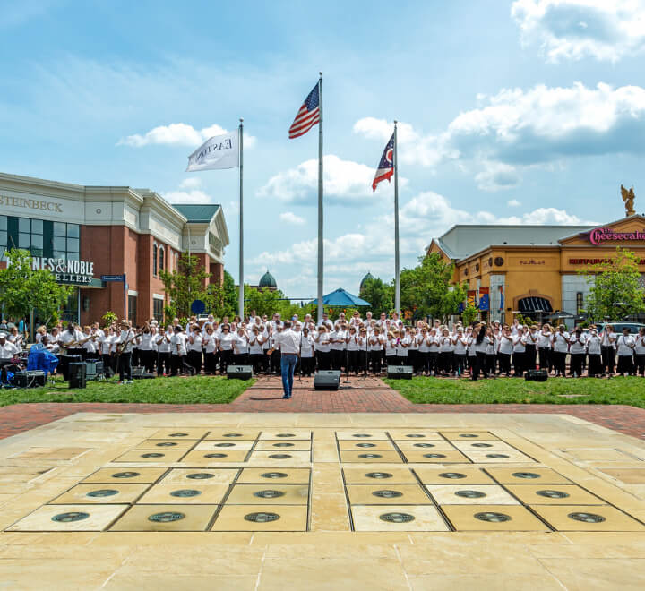 Group of people wearing white standing in front of American flag in a shopping center