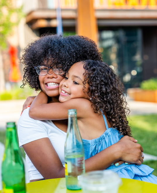 Woman hugging her daughter at a picnic table