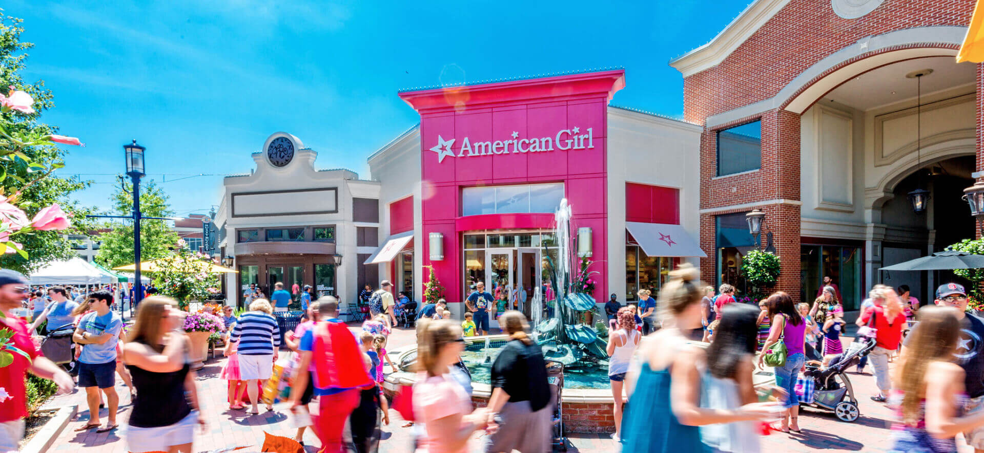 People walking in front of American Girl's pink storefront